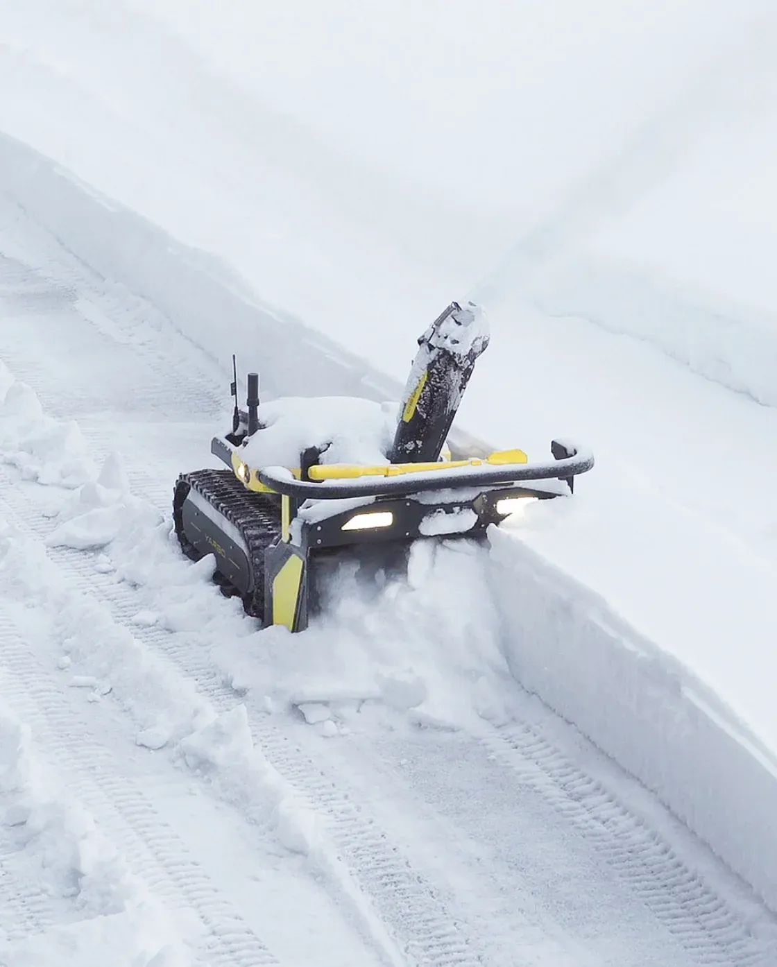 The robot, itself covered in snow, cutting through a deep snow bank